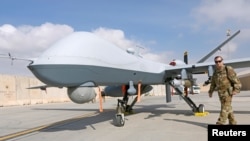 FILE - U.S. Air Force officer passes in front of a MQ-9 Reaper drone, one of a squadron that has arrived to step up the fight against the Taliban, at the Kandahar air base, Afghanistan.