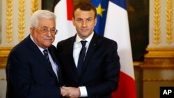 El presidente francés, Emmanuel Macron (derecha) saluda a su homólogo palestino, Mahmoud Abbas, durante una conferencia de prensa conjunta en París, el viernes 22 de diciembre.