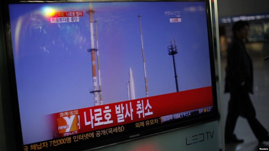 A passenger walks past a TV screen broadcasting the news that the launch of Korea Space Launch Vehicle-1 (KSLV-1) was cancelled due to a problem in the upper second-stage rocket, at a railway station in Seoul, November 29, 2012.