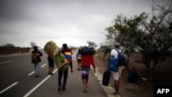 Migrantes venezolanos caminan a lo largo de una ruta, en Tumbes, Perú, cerca de la frontera con Ecuador.