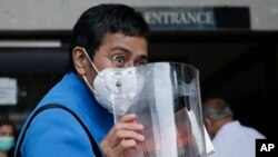 CEO dan Editor Eksekutif Rappler, Maria Ressa menunjukkan pelindung wajahnya setibanya di Pengadilan Regional Pasig Metro Manila, Filipina, Rabu, 22 Juli 2020. (AP Foto / Aaron Favila)