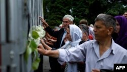 Warga muslim Bosnia menyentuh truk yang membawa 136 peti jenazah para korban kekerasan tahun 1995 di Srebrenica, di kota Visoko, dekat Sarajevo, 9 Juli 2015. (Foto: AFP PHOTO / DIMITAR DILKOFF)