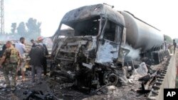 In this photo released by the Syrian official news agency SANA, Syrian security forces, emergency services and residents look at the remains of burned vehicles at the site of a bombing in Tartus, Syria, Sept. 5, 2016.