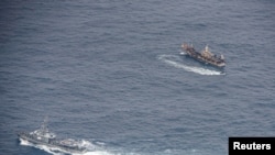 FILE - Ecuadorian navy vessels surround a fishing boat after detecting a fishing fleet of mostly Chinese-flagged ships in an international corridor that borders the Galapagos Islands' exclusive economic zone, in the Pacific Ocean, Aug. 7, 2020. 