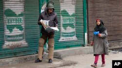 An Indian policeman reading newspaper watches a Kashmiri girl walk past him during restrictions in Srinagar, Indian controlled Kashmir, Friday, Nov. 6, 2015.