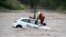 A rescue worker stands on a car to fix a tension belt to pull out the car of over-flooded areas of the river Leine in Goettingen, central Germany.