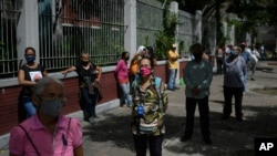 Personas con mascarillas esperan para votar durante un simulacro electoral en una escuela secundaria en Caracas, Venezuela. Octubre 25, 2020.