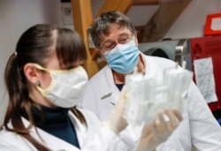 Hungarian biologists Alexandra Torok and Noemi Lukacs check the purity of an antibody, a genetic sensor of sorts, in Szirak, Hungary, Nov. 13, 2020.