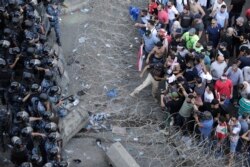 FILE - Riot police stand guard as anti-government protesters try to remove a barbed-wire barrier to advance towards the government buildings during a protest in Beirut, Lebanon, Oct. 19, 2019.