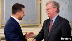 El presidente de Ucrania, Volodymyr Zelenskiy, estrecha la mano del asesor de Seguridad Nacional de la Casa Blanca, John Bolton, el miércoles, 28 de agosto, de 2019, en Kiev, Ucrania.