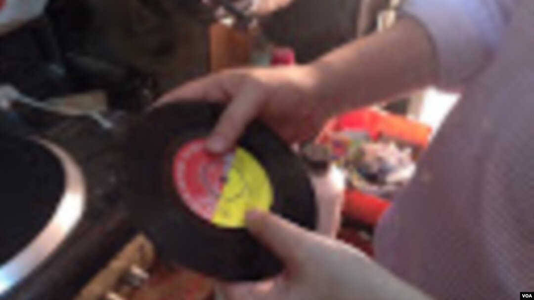 Melodica Music Store owner Abdul Karim plays a 45 RPM album recorded at the store years ago. (VOA / G. Joselow)