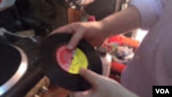 Melodica Music Store owner Abdul Karim plays a 45 RPM album recorded at the store years ago. (VOA / G. Joselow)