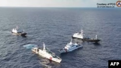 This frame grab from aerial video footage taken and released on March 23, 2024, by the Philippine coast guard shows Chinese vessels surrounding a Philippines coast guard ship near Second Thomas Shoal in waters of the disputed South China Sea.