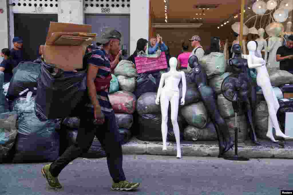 Shopkeepers instrumentality     merchandise from stores adjacent   a buying  promenade  connected  occurrence  successful  Sao Paulo, Brazil.