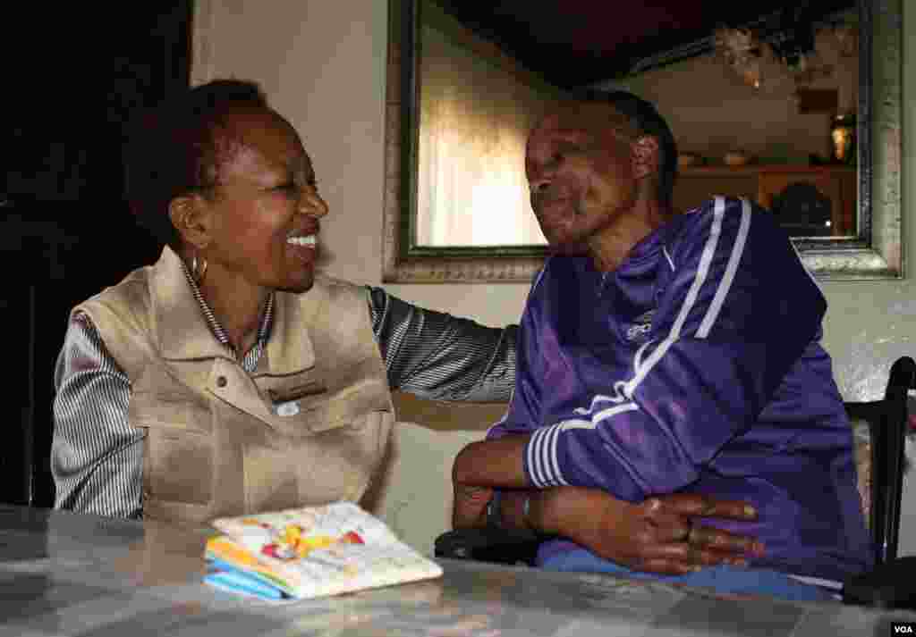 Itumeleng is comforted by palliative care nurse Snowy Nkoana (left). They laugh together over Itumeleng&#39;s steadfast dedication to complete a memory book on the table the major events in her life for her children. (Photo by Darren Taylor)