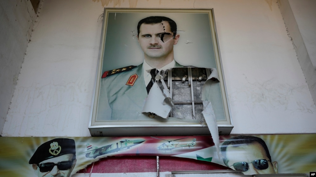 Một tấm áp phích rách nát có hình ảnh cố Tổng thống Syria Hafez al-Assad và con trai ông là Tổng thống bị lật đổ Bashar al-Assad, trên lối vào trại giam giữ an ninh khét tiếng có tên là Palestine Branch, tại Damascus, hôm 14/12/2024.