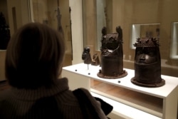 FILE - A visitor looks at two heads of a royal ancestor from the former Benin Kingdom displayed at the Quai Branly Museum in Paris, France, Nov. 23, 2018.