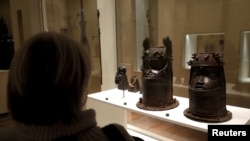 FILE - A visitor looks at two heads of a royal ancestor from the former Benin Kingdom displayed at the Quai Branly Museum in Paris, France, Nov. 23, 2018.