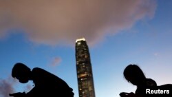 FILE - Demonstrators check their mobile phones at the site of protests against a controversial extradition bill, along a road near the Legislative Council building in Hong Kong, June 20, 2019.