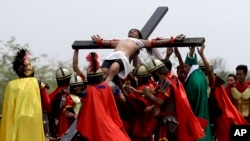 Devotees dressed as Roman soldiers lift Ruben Enaje on the cross after he was nailed to it for his 32nd time during a re-enactment of Jesus Christ's sufferings as part of Good Friday rituals in the village of San Pedro Cutud, Pampanga province, northern Philippines, March 30, 2018. 