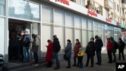 Des clients font la queue pour retirer de l'argent à un distributeur automatique d'Alfa Bank à Moscou, Russie, dimanche 27 février 2022.