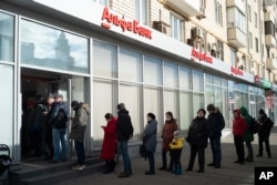 FILE - People stand in line to to take out money from an ATM of Alfa Bank in Moscow, Russia on Feb. 27, 2022. (AP Photo/Victor Berzkin, File Photo)