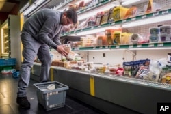 FILE - A worker removes expired food in a local supermarket in Brussels, Jan. 16, 2017.