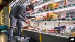 FILE - A worker removes expired food in a local supermarket in Brussels, Jan. 16, 2017.