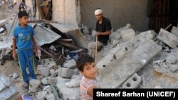 دو کودک فلسطینی در نزدیک یک ساختمان واقع در نوار غزه که توسط حملۀ هوایی اسرائیل تخریب شده