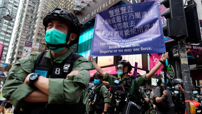 资料照片：香港警方在庆祝中国共产党建立中华人民共和国的节日期间在铜锣湾街向抗议者举出警告旗帜。(2020年10月1日)