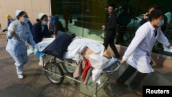 FILE - An injured woman is transferred to a hospital after an explosion at a Sinopec Corp oil pipeline in Huangdao, Qingdao, Shandong Province.