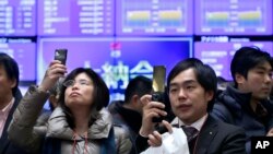 Para pengunjung mengabadikan angka-angka harga saham yang tertera pada layar di lantai bursa saham Tokyo, Minggu (30/12).Bursa Jepang ditutup lebih tinggi 57 persen, kinerja tahunan terbaik bursa itu sejak 1972.