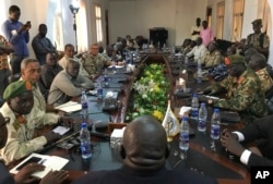 In this photo taken Nov. 22, 2018, a South Sudan armed opposition commander, Ashab Khamis, far left, and government army Gen. Keer Kiir Keer, far right, attend talks where both sides exchanged accusations of violating the peace agreement, in Wau, South Sudan.