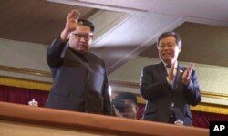 This picture captured from video footage by Korea Pool reporters shows North Korean leader Kim Jong Un (L) and South Korea's Culture, Sports and Tourism Minister Do Jong-whan (R) during a rare concert by South Korean musicians.