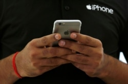 FILE - A salesman uses his iPhone at a mobile phone store in New Delhi, India, July 27, 2016. (REUTERS/Adnan Abidi)