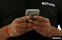 FILE - A salesman uses his iPhone at a mobile phone store in New Delhi, India, July 27, 2016. (REUTERS/Adnan Abidi)