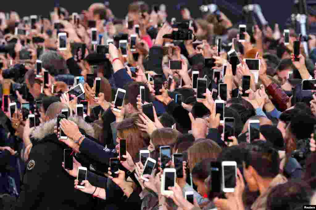 Para penonton menggunakan smartphone untuk mengabadikan acara pameran busana di Champs Elysees avenue di Paris, Perancis.