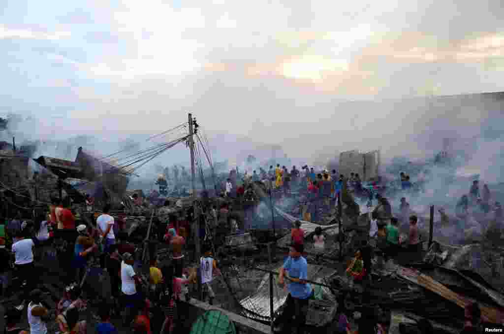 Warga berkumpul di sekitar puing-puing rumahnya setelah terjadi kebakaran di lingkungan pemulung di Navotas, Metro Manila, Filipina.