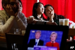 FILE - Students watch a live broadcast of the presidential debate between Democratic presidential candidate Hillary Clinton and Republican presidential candidate Donald Trump, at a cafe in Beijing.