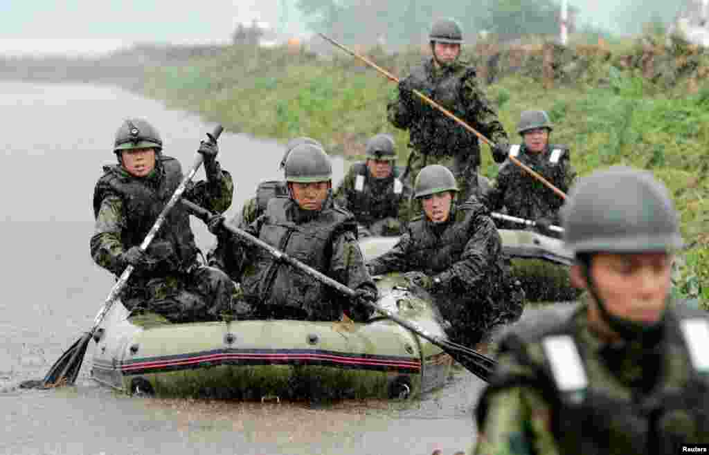 Tentara Jepang menggunakan perahu karet untuk mencari orang hilang di wilayah yang terkena tanah longsor akibat hujan lebat di Aso, Kumamoto.