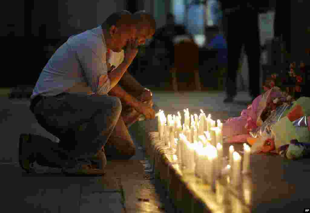 A man holds back tears as he lights candles for victims of an attack at the Resorts World Manila complex, in Manila, Philippines. Police say a gunman stormed a crowded casino and used gasoline to set gambling tables on fire, creating clouds of smoke that swept through the crowds and killed dozens of people.