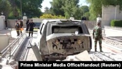 A destroyed vehicle is parked in front of Iraqi Prime Minister Mustafa al-Kadhimi's residence following an assassination attempt by an armed drone in Baghdad, Iraq in this screen grab taken from a handout video, Nov. 7, 2021.