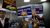 FILE - Real estate agents hold foreign properties promotion sales placards at an entrance to the China Property and Investment Show in Beijing.