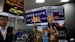 FILE - Real estate agents hold foreign properties promotion sales placards at an entrance to the China Property and Investment Show in Beijing.