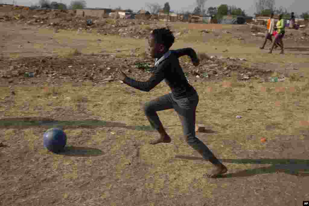 A child plays soccer in the Diepsloot Township, north of Johannesburg, Thursday, Aug. 26, 2021. (AP Photo/Denis Farrell)