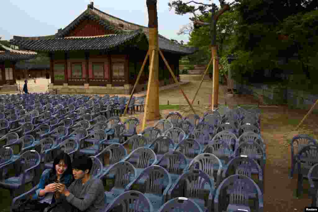 Sepasang kekasih menggunakan smartphone mereka sambil menunggu pertunjukkan shadow play di Istana Changgyeonggung di Seoul.