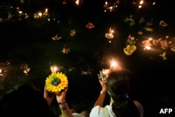 Two women prepare to release 'krathong' on a lake at a park to celebrate Loi Krathong festival in Bangkok on Nov. 22, 2018.