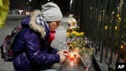 A Ukrainian woman lights a candle in front of the Russian Embassy in Kyiv to pay tribute to victims of a Russian plane crash in the Sinai Peninsula, Oct. 31, 2015.