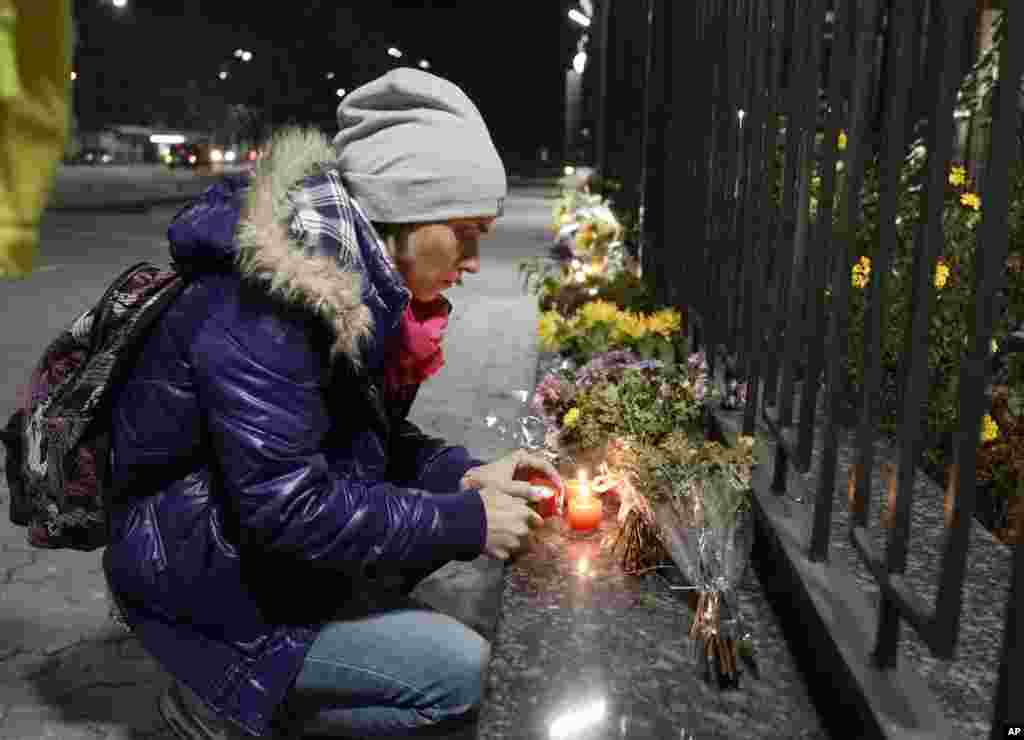 کیئف میں روسی سفارتخانے کے سامنے ایک خاتون مسافر طیارے میں ہلاک ہونے والوں کی یاد میں شمع روشن کر رہی ہے۔