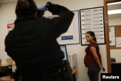 A pregnant woman who is seeking asylum has her picture taken by a U.S. Customs and Border patrol officer at a pedestrian port of entry from Mexico to the United States, in McAllen, Texas, May 10, 2017.